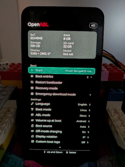 A photo of a SHIFT6mq in a LEGO "dock". The screen shows OpenABL with a "Phosh BengalOS roaming" boot menu entry.